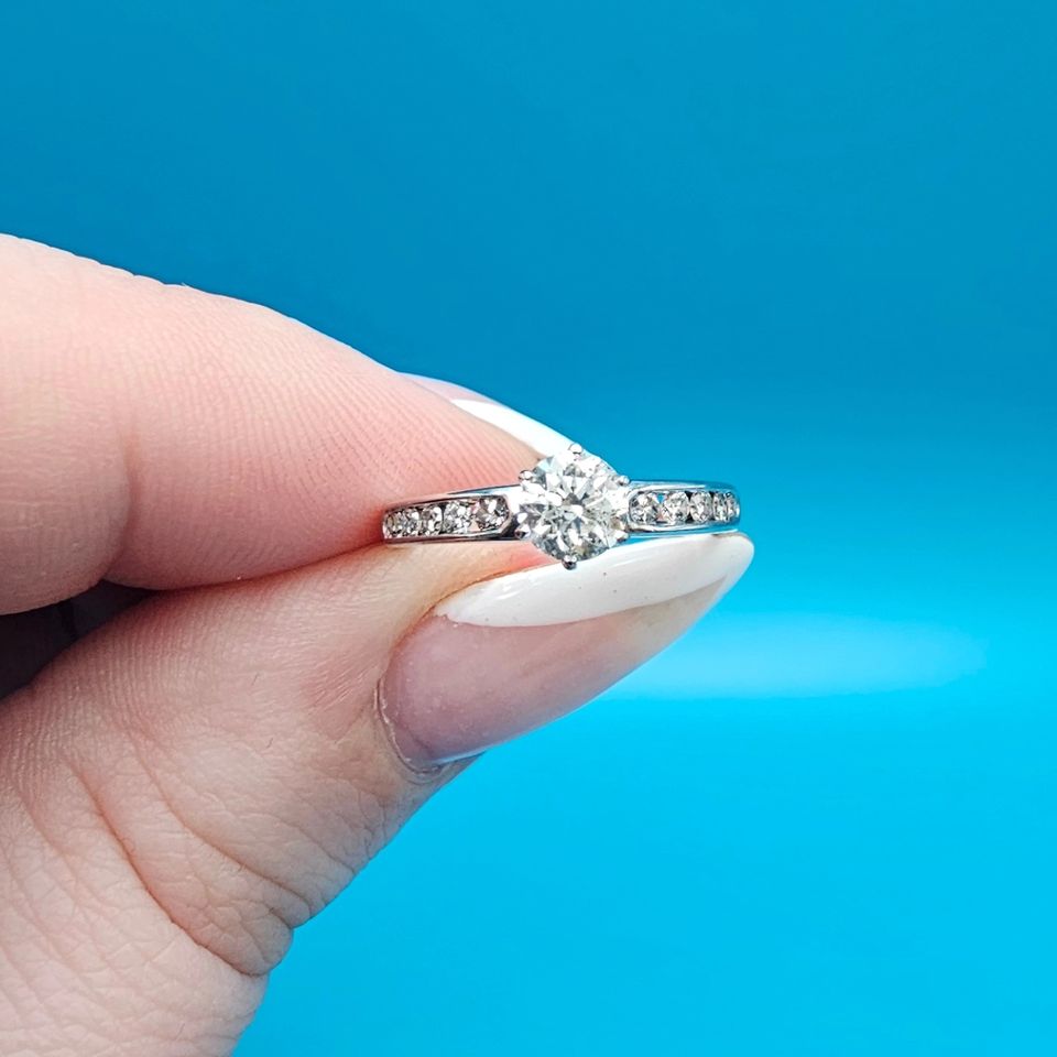 14k white gold engagement ring set with 1 round  (0.51ct) diamond and 10 diamonds surround it.