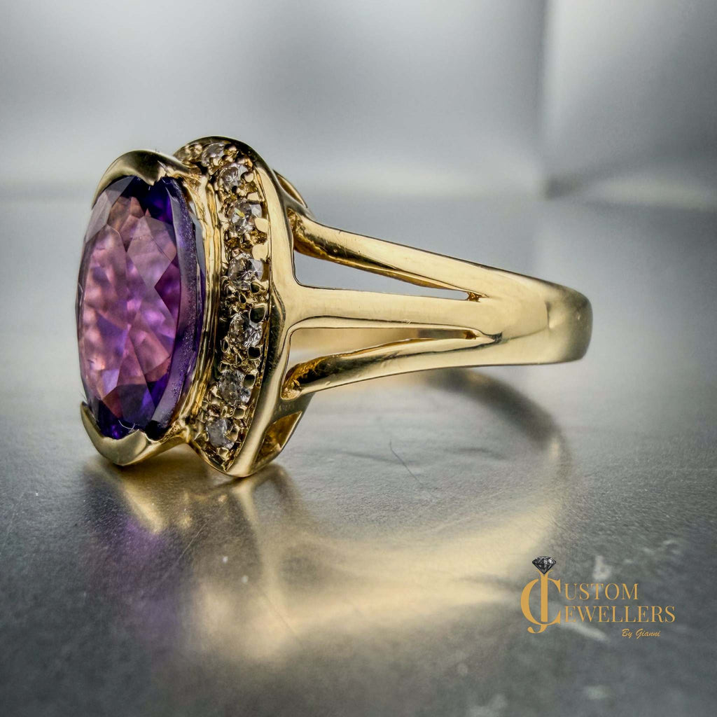 A yellow gold ring featuring a large oval-cut purple amethyst centre stone, accented by small diamonds set along a half-halo edge.