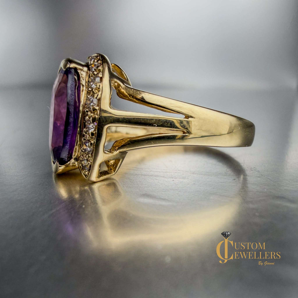 A yellow gold ring featuring a large oval-cut purple amethyst centre stone, accented by small diamonds set along a half-halo edge.