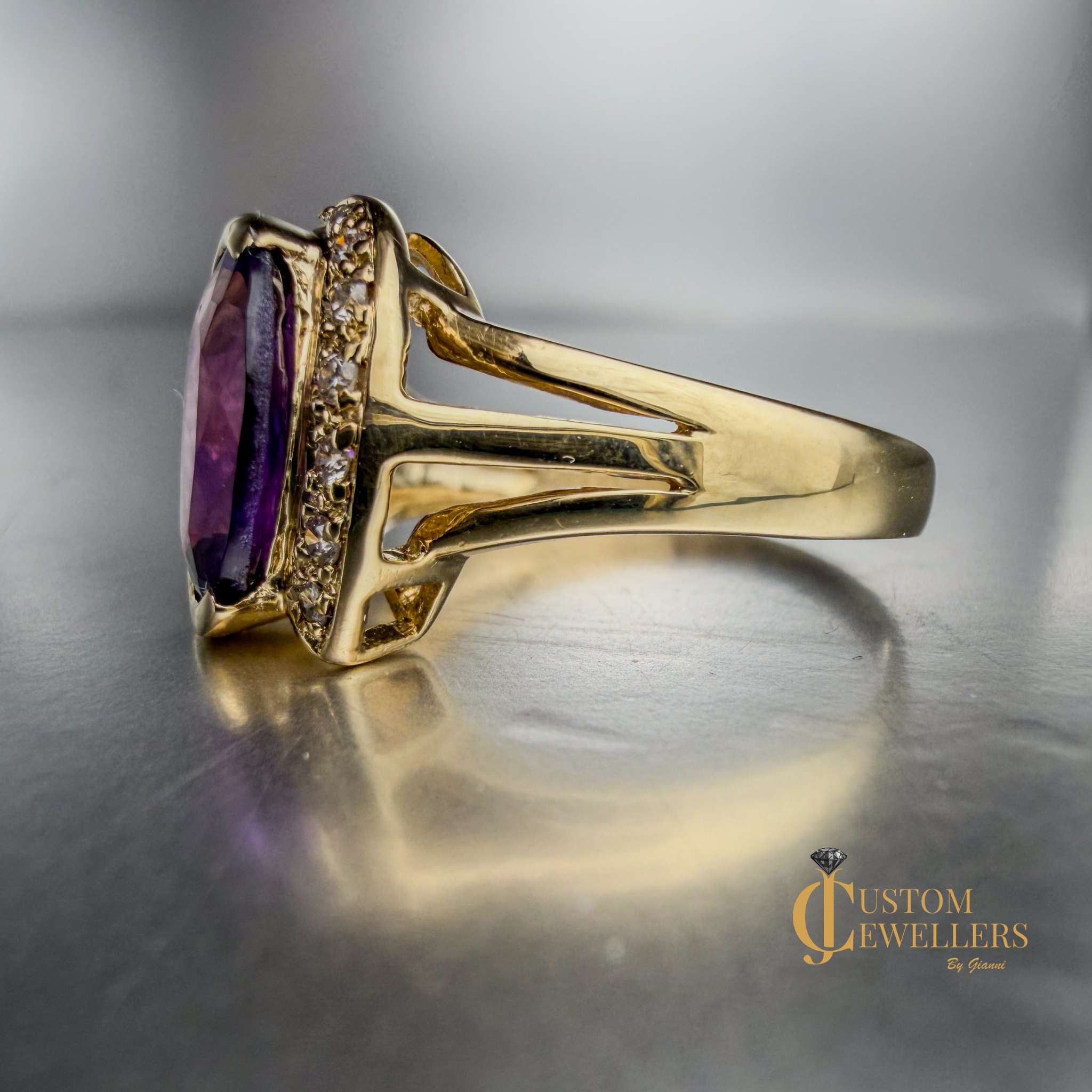 A yellow gold ring featuring a large oval-cut purple amethyst centre stone, accented by small diamonds set along a half-halo edge.