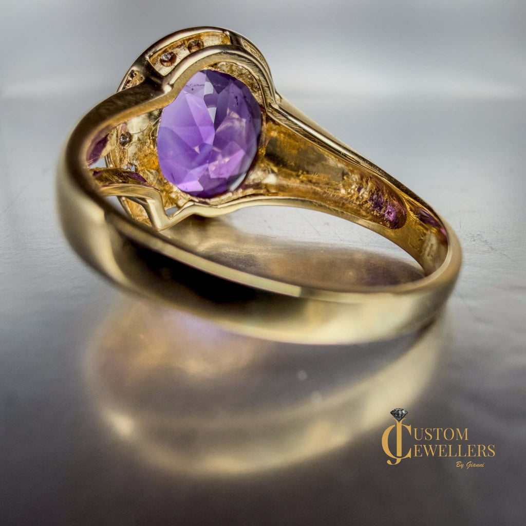 A yellow gold ring featuring a large oval-cut purple amethyst centre stone, accented by small diamonds set along a half-halo edge.