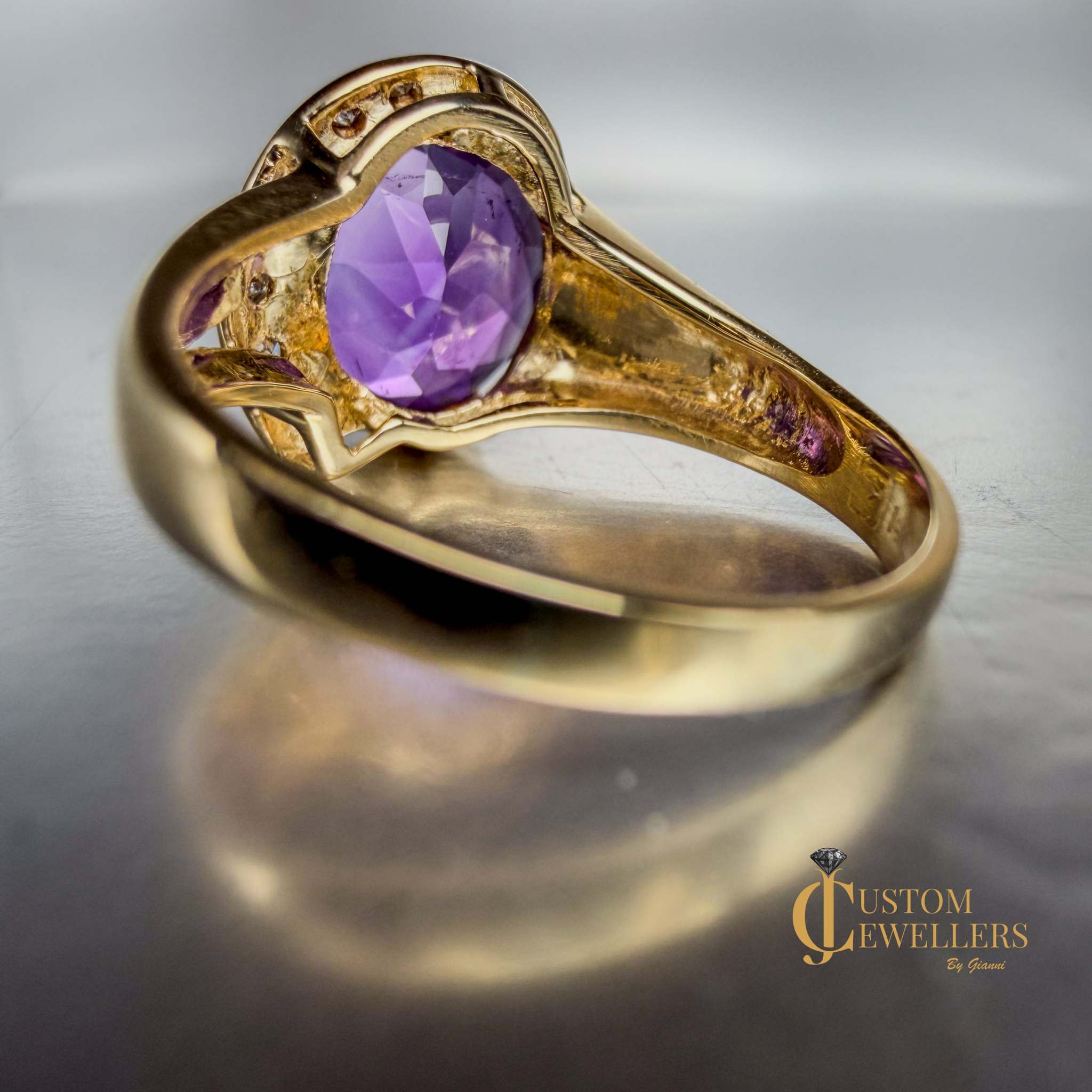 A yellow gold ring featuring a large oval-cut purple amethyst centre stone, accented by small diamonds set along a half-halo edge.
