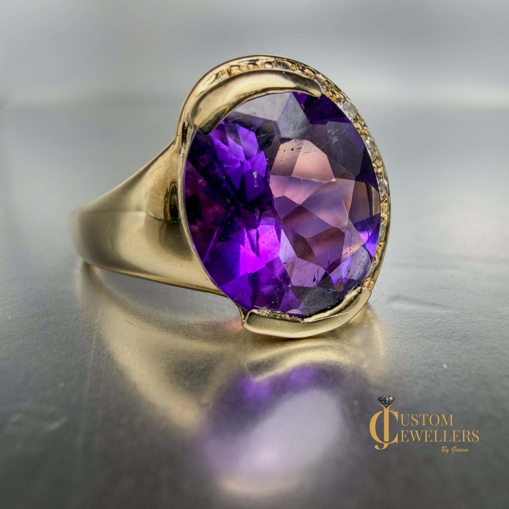 A yellow gold ring featuring a large oval-cut purple amethyst centre stone, accented by small diamonds set along a half-halo edge.