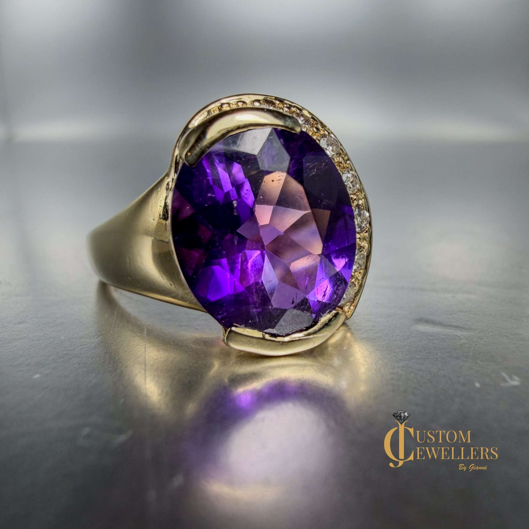 A yellow gold ring featuring a large oval-cut purple amethyst centre stone, accented by small diamonds set along a half-halo edge.
