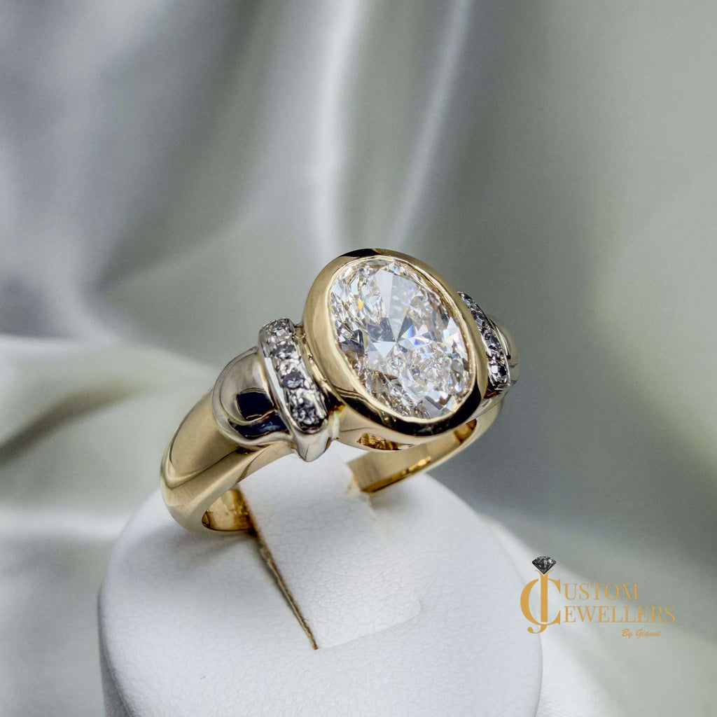 Hand assembled custom VVS2 diamond ring in 14k yellow gold with lab-grown oval bezel diamond and eight shoulder diamonds