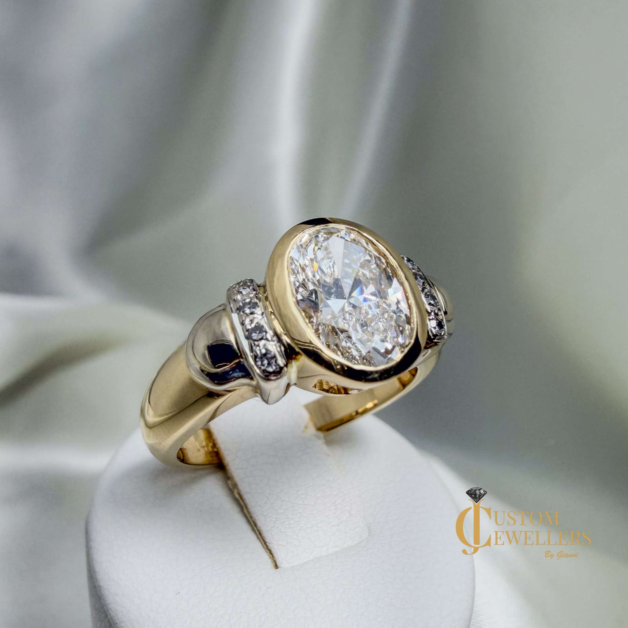 Hand assembled custom VVS2 diamond ring in 14k yellow gold with lab-grown oval bezel diamond and eight shoulder diamonds