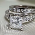 18k White Gold Bridal Rings with a princess-cut diamond solitaire and coordinating bands set with sparkling stones.