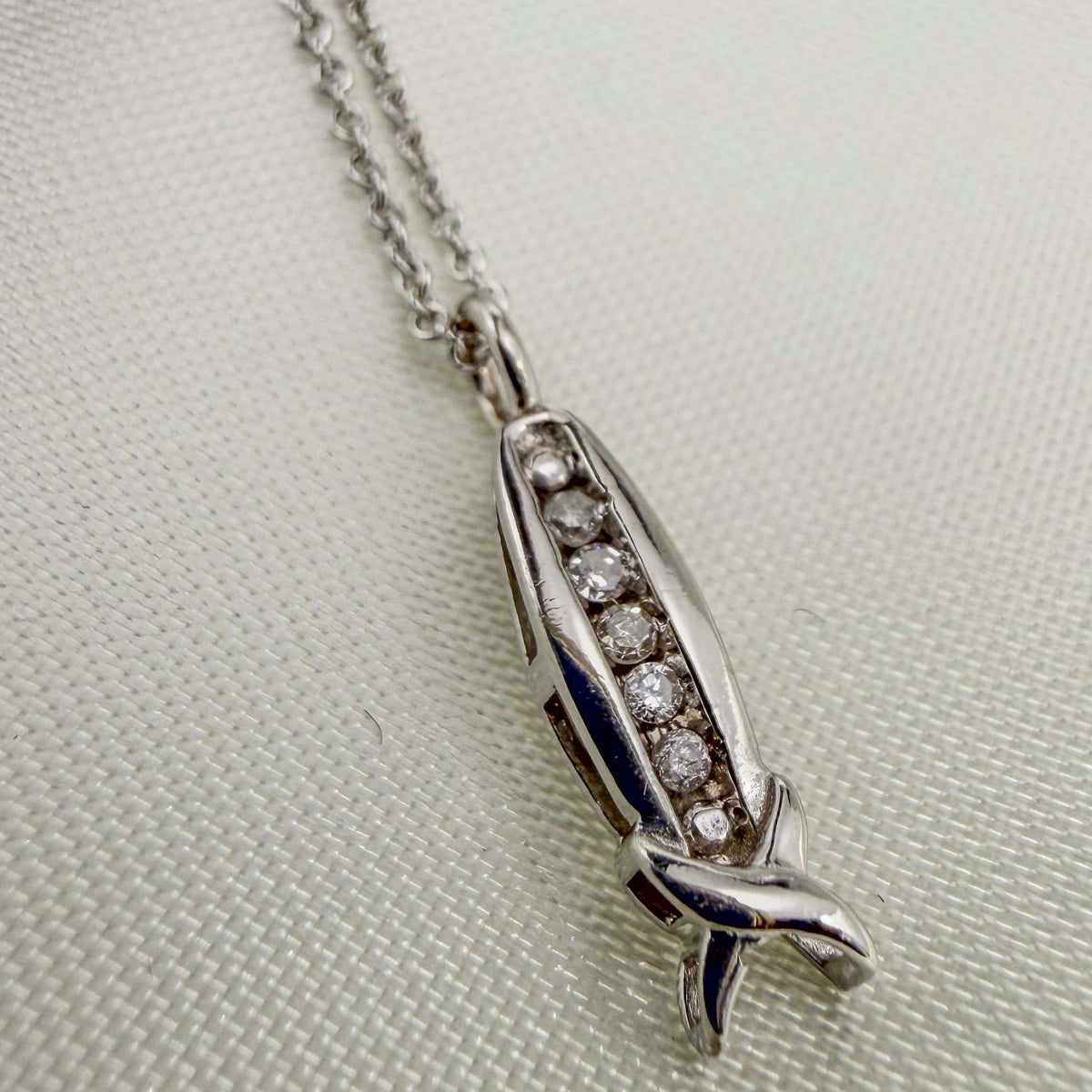 Diamond Channel 10k White Gold pendant necklace with a slim channel of round diamonds and a sculpted, crossed-end design.