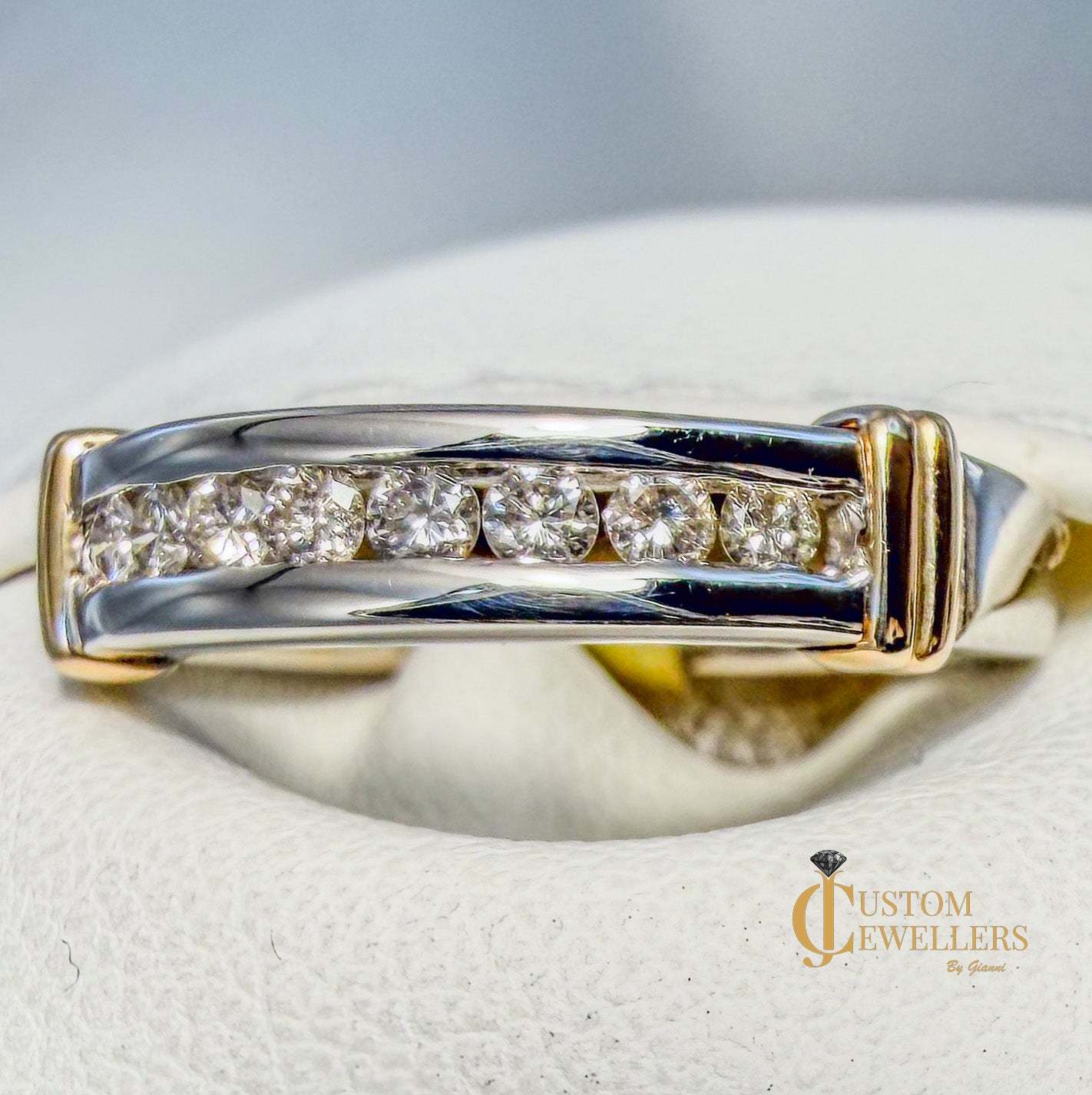 Yellow and white gold ring on a white cushion with 'Custom Jewellers' branding.