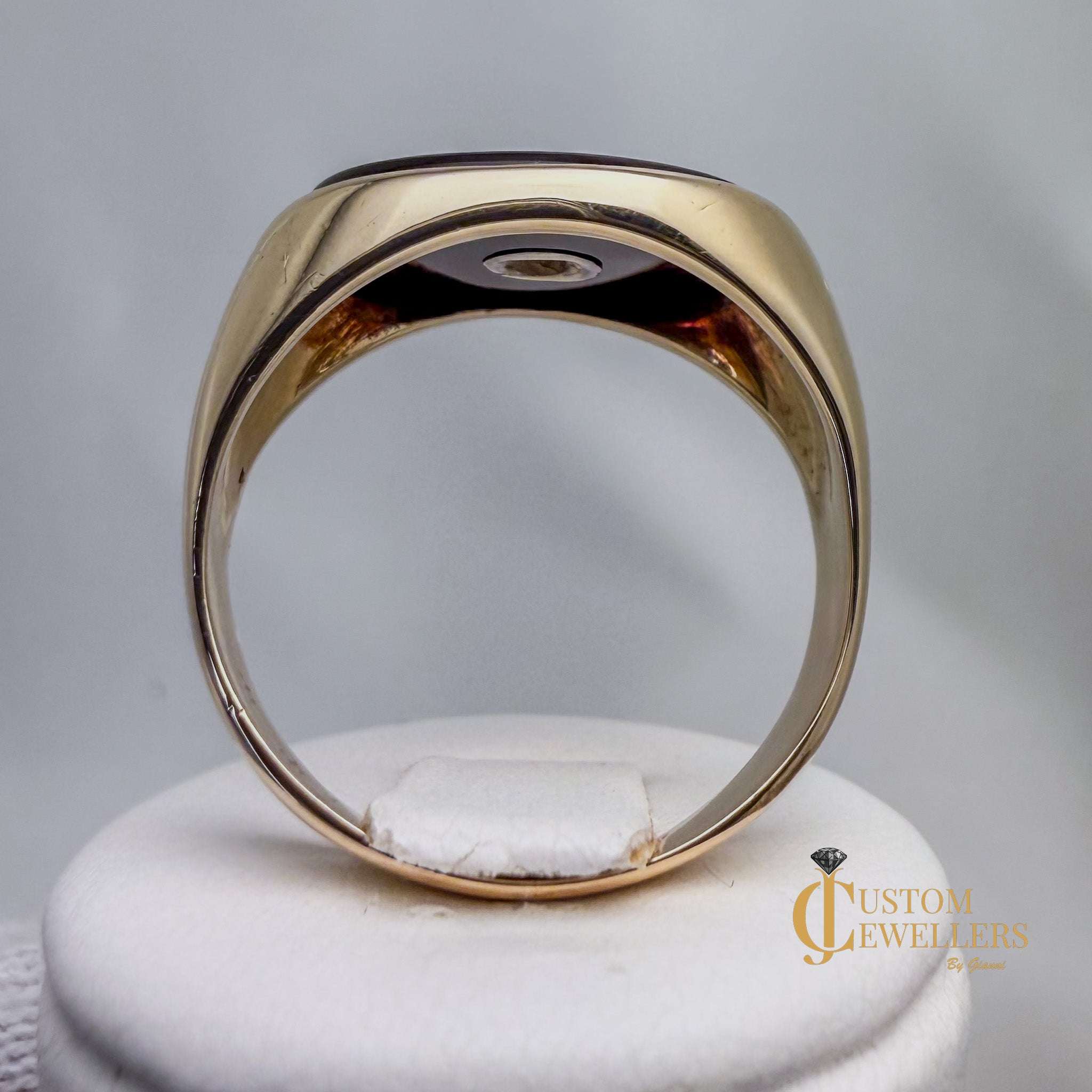 Gold ring on a white stand with 'Custom Jewellers' branding.