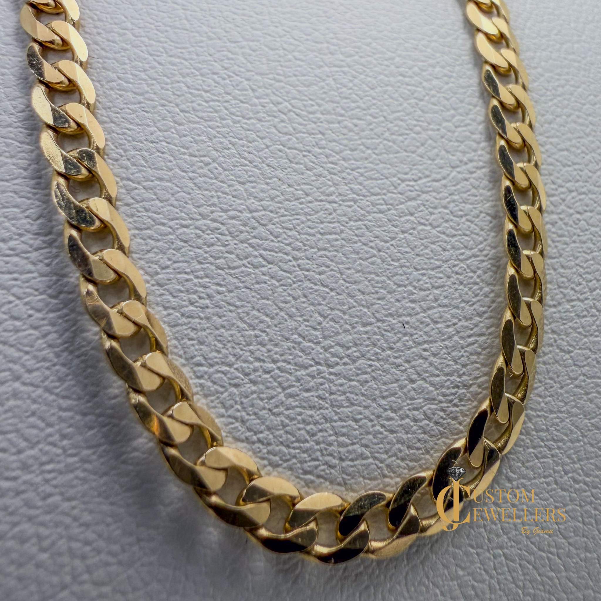 Gold chain necklace on a textured gray background with 'Custom Jewellers' branding.