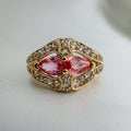 Gold ring with Extremely Rare Padparadscha Sapphires, pink marquise-cut stones, white sapphire halo and ornate engraved floral details.