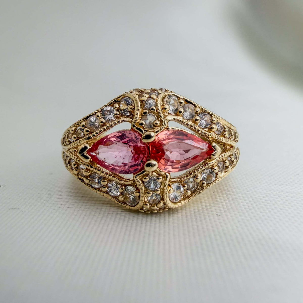 Gold ring with Extremely Rare Padparadscha Sapphires, pink marquise-cut stones, white sapphire halo and ornate engraved floral details.