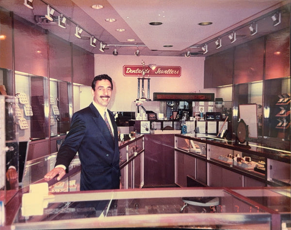 John smiling behind the showcase at Donlands Jewellers, 1990s
