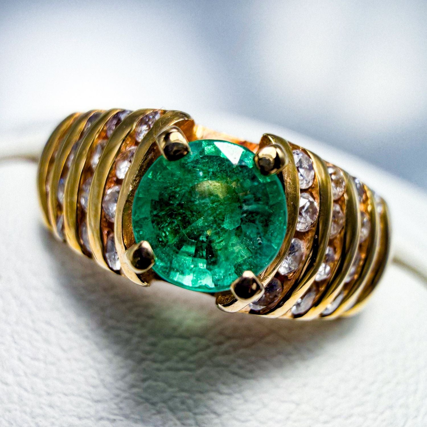 Yellow gold ring with a green centre stone and rows of white stones