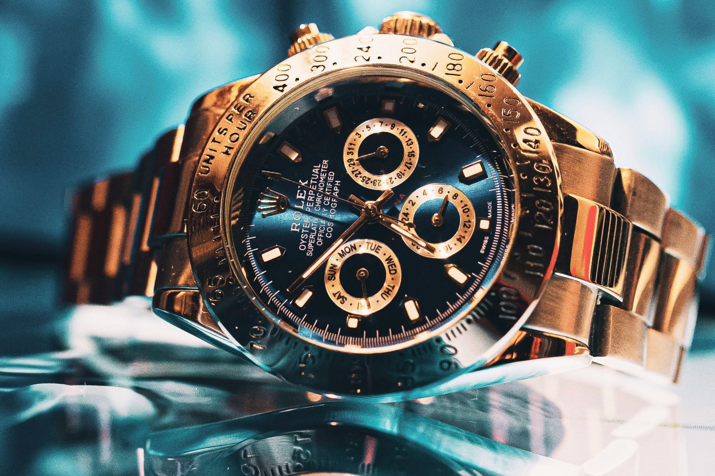 Gold Rolex wristwatch with a reflective surface and blurred background